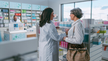 Obraz premium Pharmacy Drugstore: Beautiful Senior Woman Chooses to Buy Medicine, Drugs, Vitamins, Professional Pharmacist Helping Customer with Recommendation. Modern Pharma Store Shelves with Health Care Products