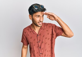 Young handsome man wearing casual summer clothes very happy and smiling looking far away with hand over head. searching concept.