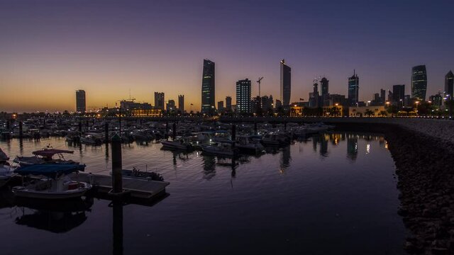 Yachts and boats at the Sharq Marina with city skyline night to day transition timelapse in Kuwait. Reflection in the water. Kuwait City, Middle East.