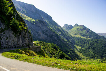  Mountain road surrounded by green meadows through the French Pyrenees. High quality photo. Copy Space for characters or letters