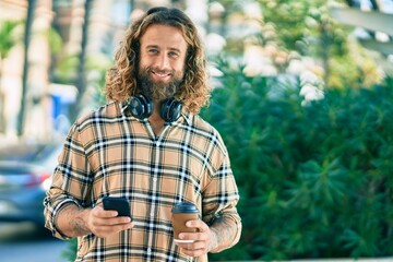 Young caucasian man using smartphone drinking coffee at the park.