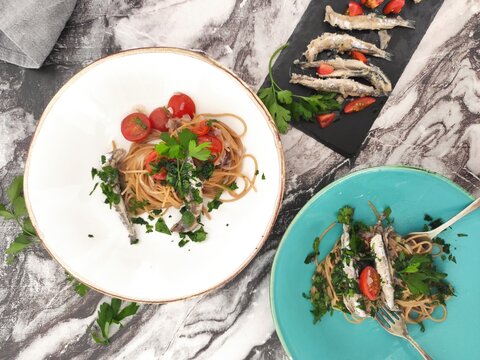 Italian spaghetti from top with sardines, cherry tomatoes and a lot of parsley
