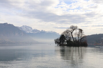 Le lac d'Annecy entouré de montagnes sous un ciel nuageux, ville de Annecy, département de Haute Savoie, France