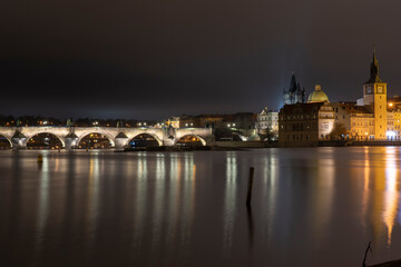 Fototapeta na wymiar stone illuminated Charles Bridge and bridge tower on the Vltava river in the center of Prague at night and illuminated by street lights