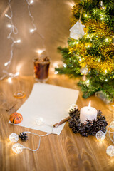 A blank sheet of paper under the christmas tree. A letter to Santa Claus. Christmas decor on a wooden table