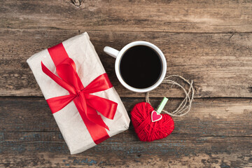 Gift box, coffee cup and heart on wooden background. Concept of February 14, love.