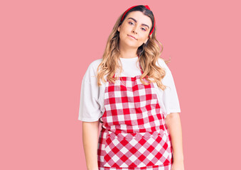 Young caucasian woman wearing apron relaxed with serious expression on face. simple and natural looking at the camera.