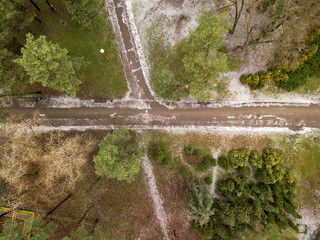 Aerial drone top view. The paths in the park are covered with a thin layer of snow.