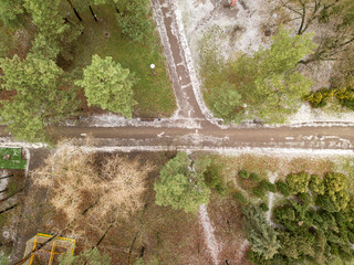 Aerial drone top view. The paths in the park are covered with a thin layer of snow.