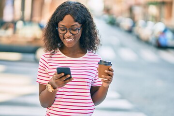 Young african american girl using smartphone drinking coffee at the city.