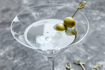 Glass of tasty martini with olives on grunge background