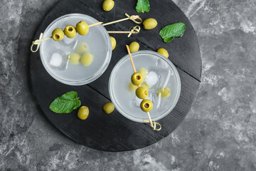 Glasses of tasty martini with olives on grunge background