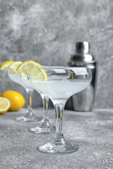 Glasses of tasty martini with lemon on grunge background