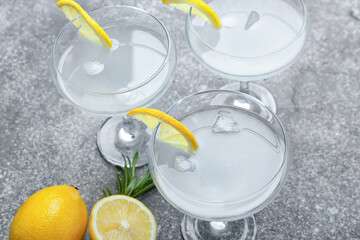 Glasses of tasty martini with lemon on grunge background