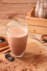 Glass of aromatic chocolate milk on wooden background