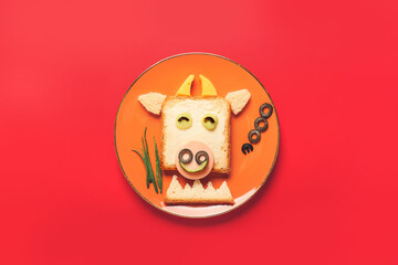 Plate with tasty sandwich in shape of bull on color background