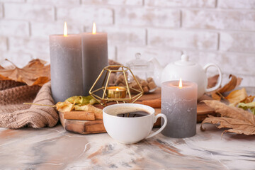Obraz na płótnie Canvas Beautiful aroma candles with autumn leaves and coffee on table