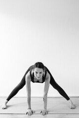 A brunette woman in her 30’s practicing yoga at home. One woman concentrated on a aide-legged forward bend asana, or yoga posture. Vertical view.