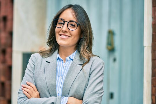 Young hispanic businesswoman with arms crossed smiling happy at the city
