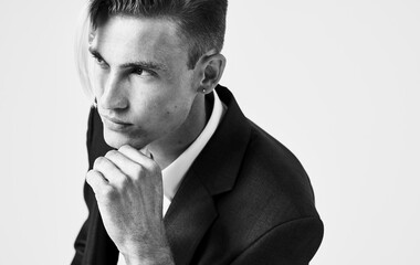 Handsome young man holds his hand near his face on a light background cropped view of a suit