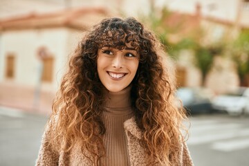 Young hispanic woman smiling happy standing at the city