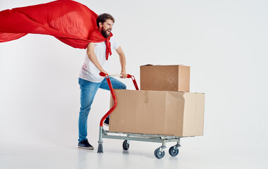 courier with cardboard boxes in cargo trolley and red superhero cloak