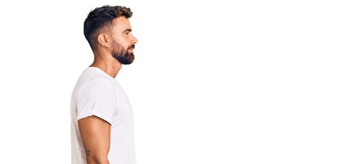 Young hispanic man wearing casual white tshirt looking to side, relax profile pose with natural face with confident smile.