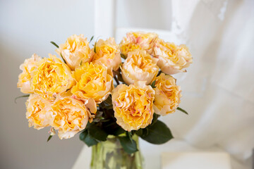 Bouquet of orange roses Candlelight on the white wooden chair next to white wall.