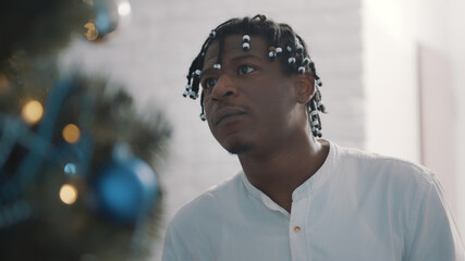 Young african american black man with braided hair decorating the christmas tree, Close up. High quality photo