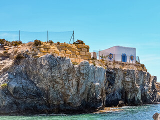 Rock cliff with building in bay of Mediterranean sea