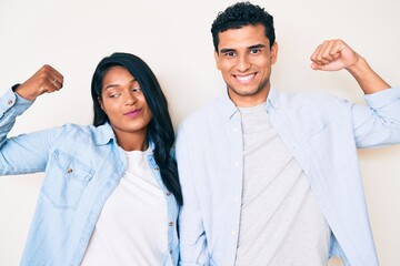 Beautiful latin young couple wearing casual clothes showing arms muscles smiling proud. fitness concept.