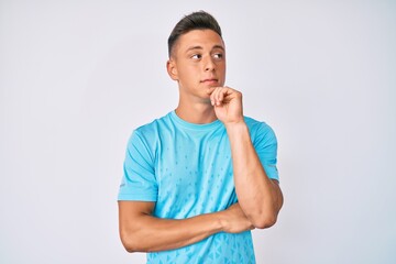 Young hispanic boy wearing casual clothes serious face thinking about question with hand on chin, thoughtful about confusing idea