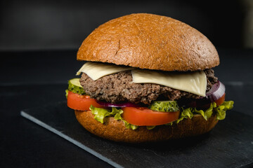 Huge delicious Burger on a dark background. Meat and vegetables.
