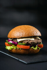 Huge delicious Burger on a dark background. Meat and vegetables.