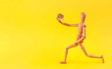 The wooden man stands in a pose and holds out a gift.