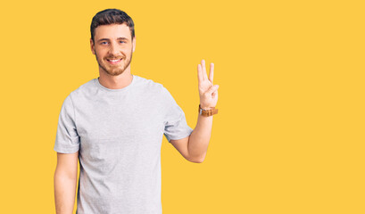 Handsome young man with bear wearing casual tshirt showing and pointing up with fingers number three while smiling confident and happy.