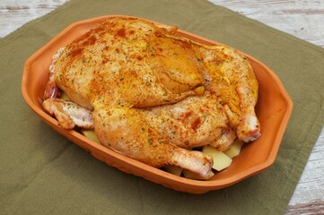 chicken ready for roasting lying in a Roman pot