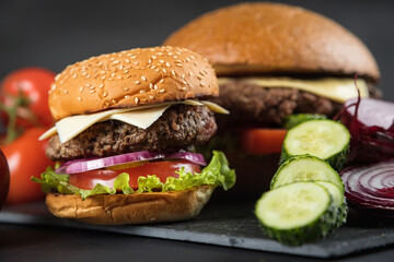 Huge delicious Burger on a dark background. Meat and vegetables.
