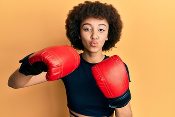Young hispanic sporty girl using boxing gloves looking at the camera blowing a kiss being lovely and sexy. love expression.