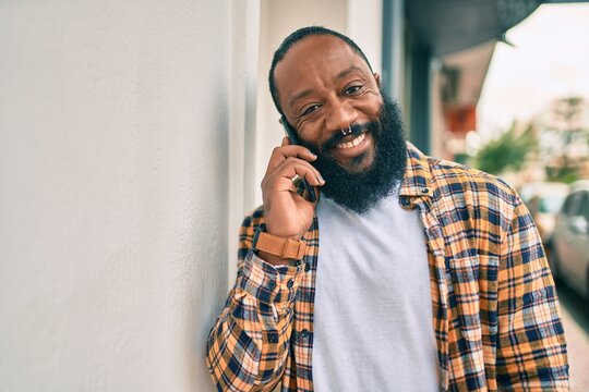 Handsome modern african american man with beard speaking on the phone at the city with a happy smile