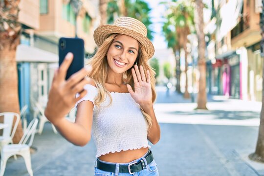 Young blonde tourist girl smiling happy doing video call using smartphone at the city.