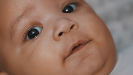 Happy newborn dark skin baby smiling on the blanket. Close up. High quality photo