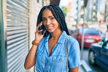 Young african american woman smiling happy talking on the smartphone at the city.