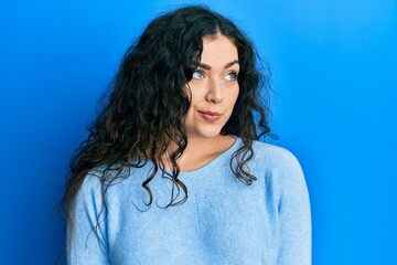 Young brunette woman with curly hair wearing casual clothes smiling looking to the side and staring away thinking.