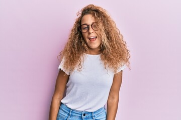 Beautiful caucasian teenager girl wearing white t-shirt over pink background winking looking at the camera with sexy expression, cheerful and happy face.