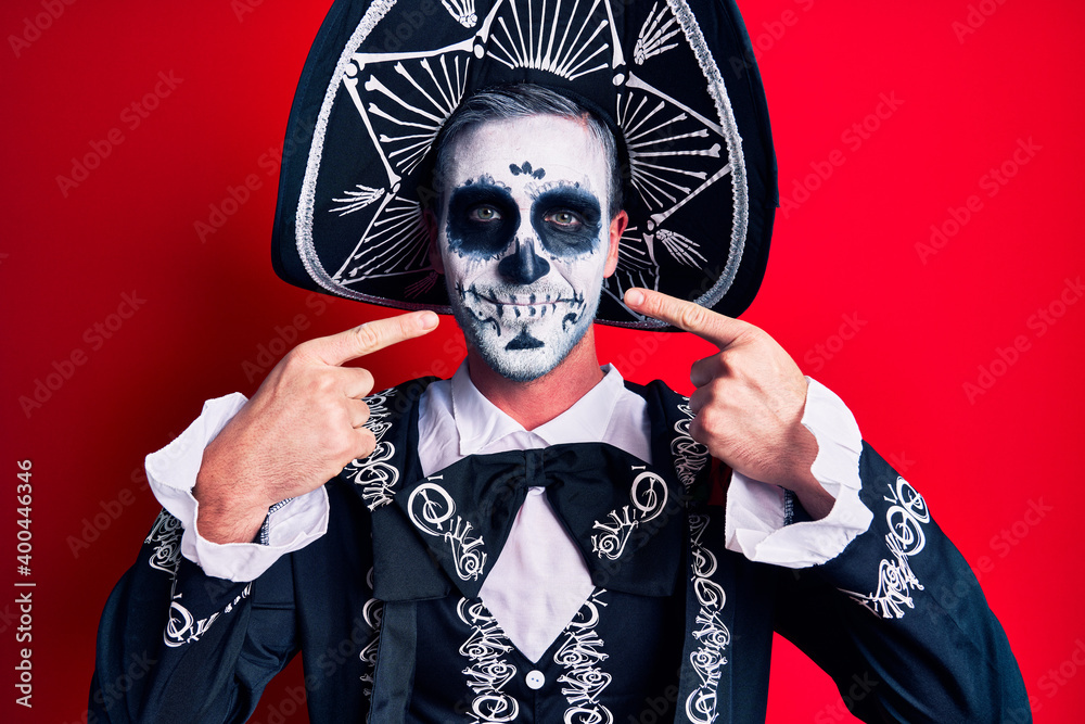 Canvas Prints Young man wearing mexican day of the dead costume over red smiling cheerful showing and pointing with fingers teeth and mouth. dental health concept.