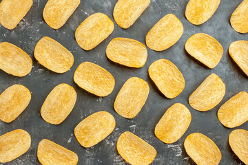 Close up view of delicious homemade potato chips laid on gray background