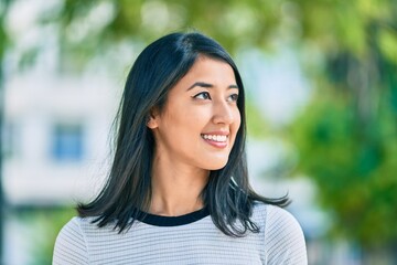 Young hispanic woman smiling happy walking at the park.