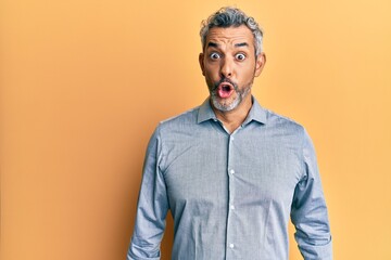 Middle age grey-haired man wearing casual clothes scared and amazed with open mouth for surprise,...
