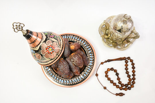 Natural dried dates (fruits of date palm Phoenix dactylifera) in traditional hand made cooper bowl with Turkish coffee and prayer-beads. isolated on white background
